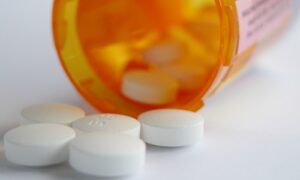 medications in front of an open pill bottle on it side